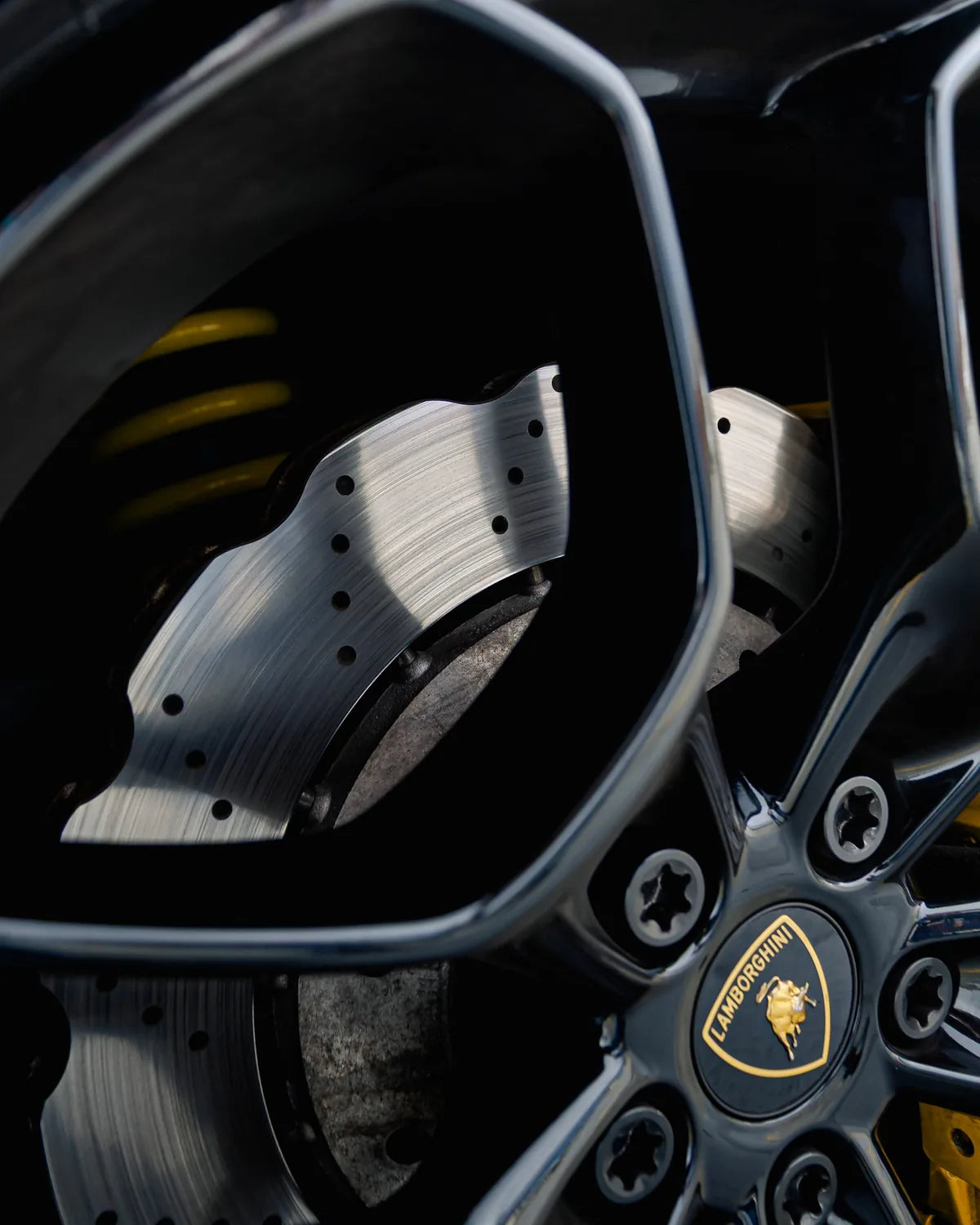 Close-up of a sports-car wheel, brake disc, and yellow caliper