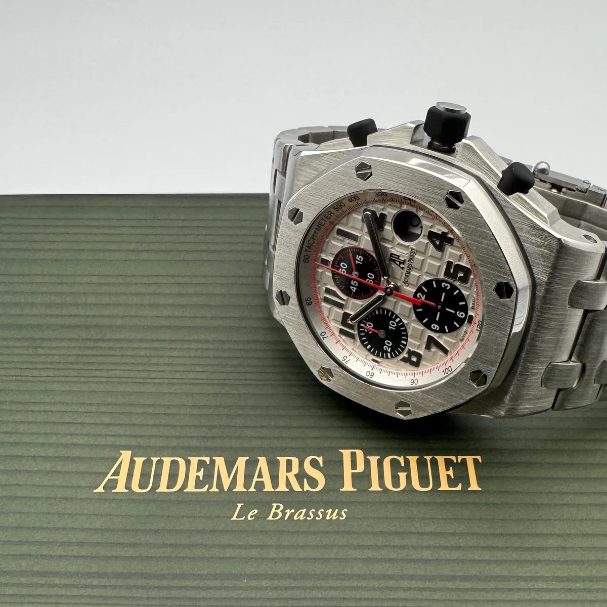 Close-up of a steel chronograph resting on a green presentation surface